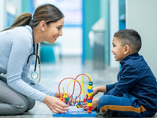 Nurse and child patient smiling at each other while playing